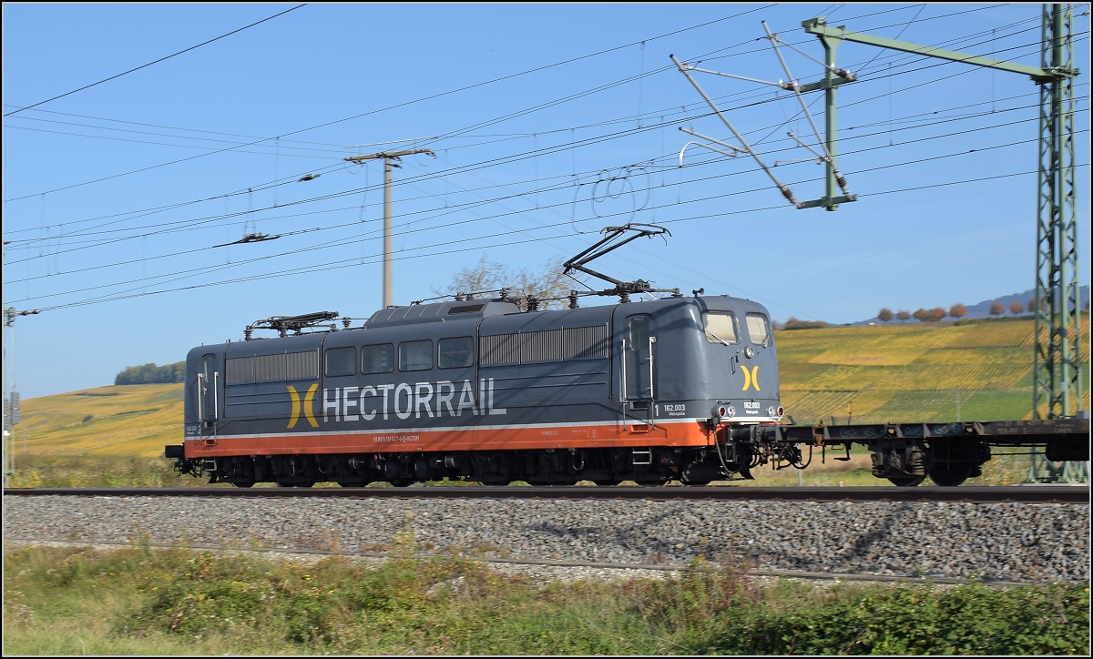 Bahn im Markgräflerland. 151 027  Metropolis  zieht einen Güterzug nordwärts und fädelt in die Altstrecke der badischen Hauptbahn ein. Schliengen, Oktober 2017.