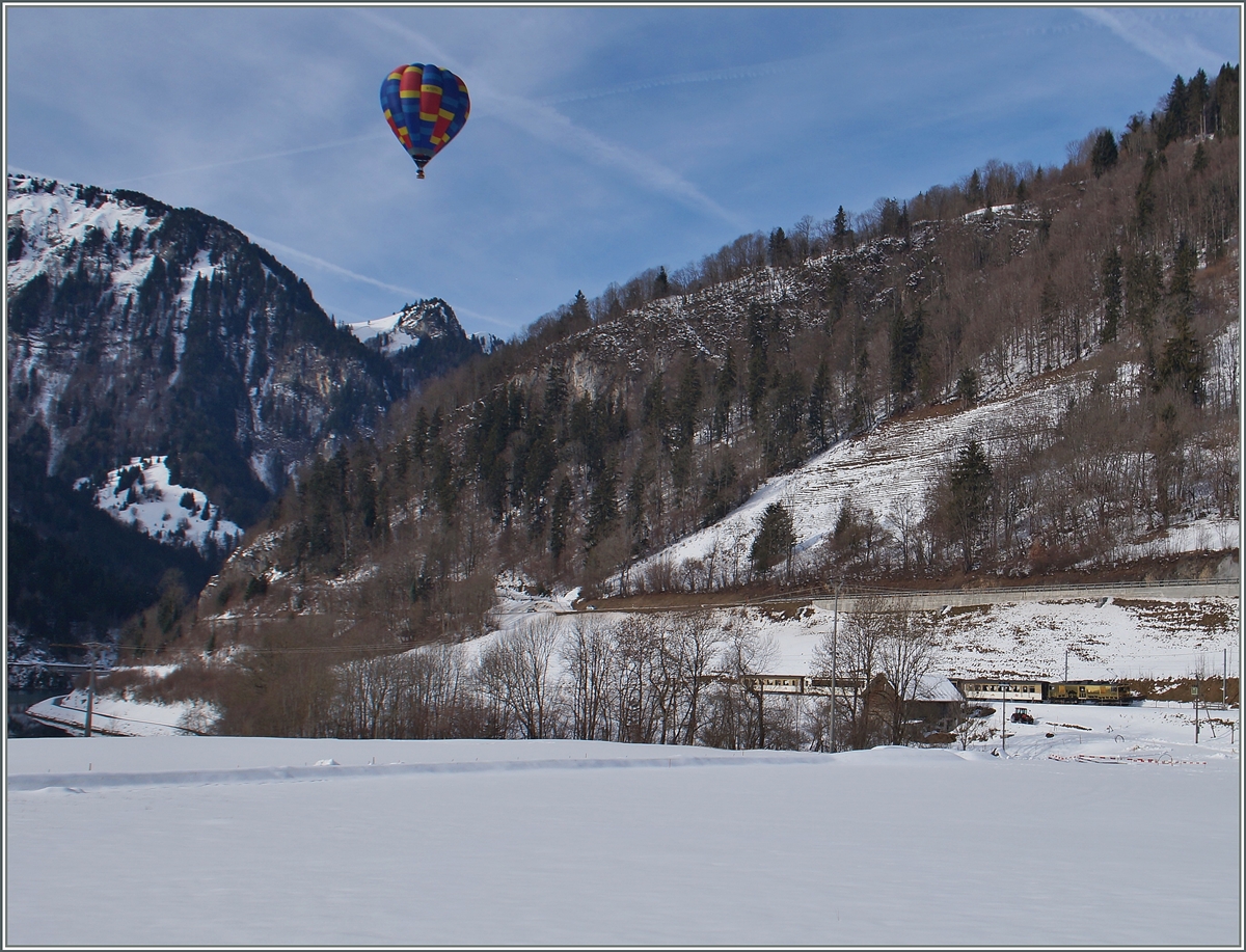 Ballon Festival 2016 Château d'Oex: Während der kaum zu sehende MOB Regionalzug 2222 von Montreux nach Zweisimmen in Kürze Rossinère erreichen wird. Schwebt ein Heissluftballon fast lautlos westwärts.
26. Jan. 201