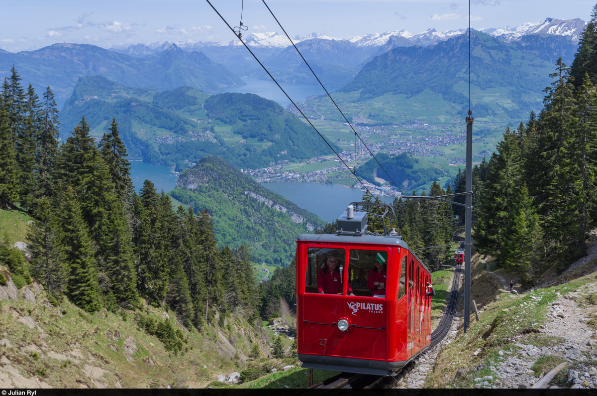 Bhe 1/2 27 fährt am 10. Mai 2015 oberhalb der Zwischenstation Ämsigen bergwärts. Im Hintergrund der Alpnacher- und der Vierwaldstättersee, sowie der Bürgenstock und das Gotthardmassiv.