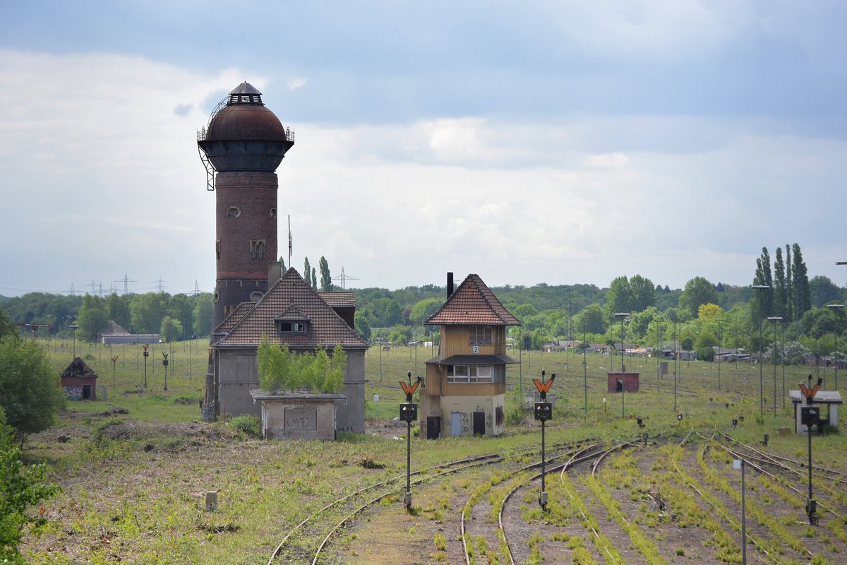 Blick auf einen von zwei alten Wassertürmen und dem Stellwerk. Im Hintergrund ist die gerodete Fläche des alten Güterbahnhofes zu sehen. Man könnte meinen dort stände niemals ein Wald. In seiner Lebenszeit war der Güterbahnhof noch mit Oberleitung überspannt. Heute sind davon nur die Mastfundamente übrig. Hier soll in Zukuft ein Gewerbepark entstehen. Somit ist das Schicksal für den Güterbahnhof besiegelt. Nur einige Gebäude könnten erhalten bleiben da sie unter Denkmalschutz stehen.

Duisburg Wedau 14.05.2016