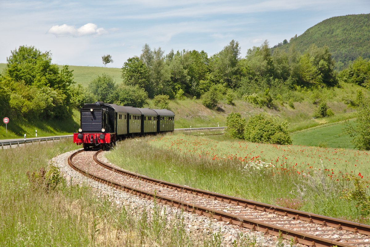 Da am 5/6. Juni keine Dampflok auf der Wutachtalbahn verfügbar war, kam stattdessen die ehemalige Wehrmachtsdiesellok V36 204 zum Einsatz. Aufgrund der deutlichen geringen Leistungsfähigkeit der Diesellok musste der Zug auf 4 3-Achser verkürzt werden.
Entstanden ist die Aufnahme im Gleisbogen bei Epfenhofen am 6.06.2014.