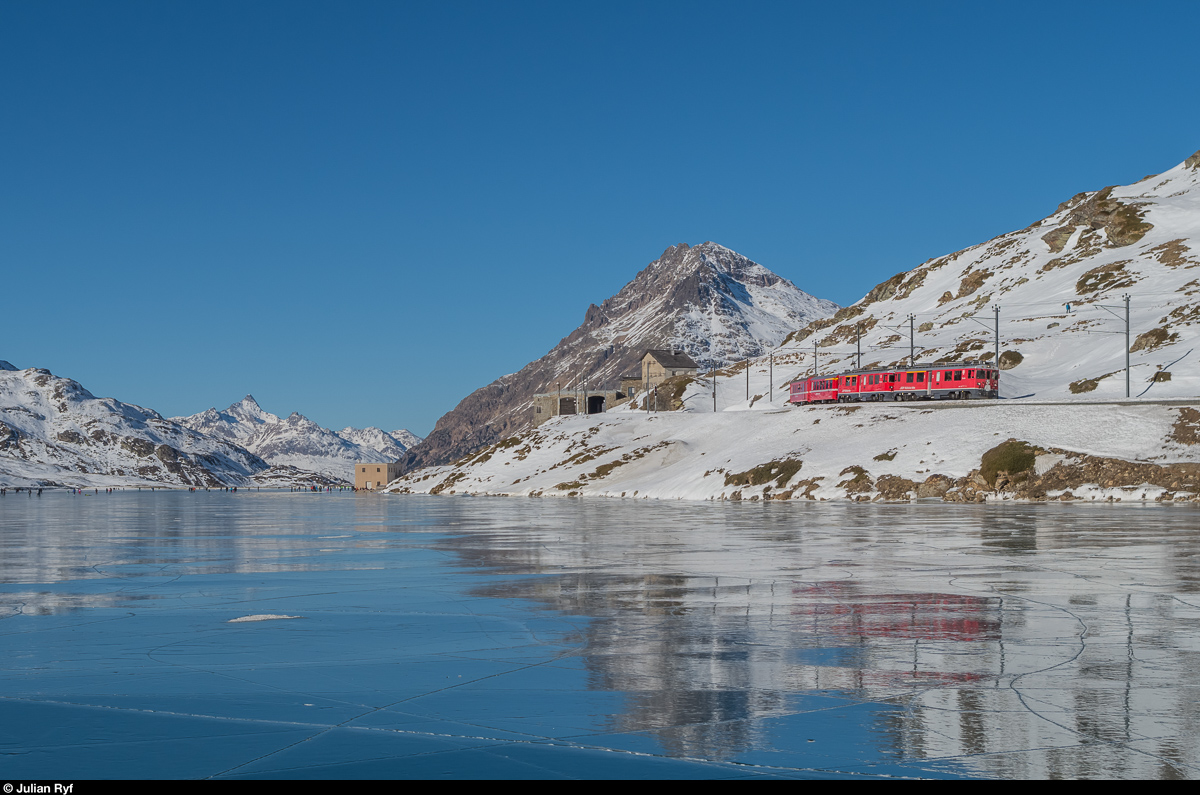 Dank Schlittschuhen und vielen Aussteigern konnte der am Bahnhof Ospizio Bernina haltende Regio 1629 überholt und nach der Abfahrt noch einmal abgelichtet werden. Auf dem Lago Bianco tummelten sich am 29. Dezember 2016 zwischen 100 und 200 Leute!<br>
ABe 4/4 III 52  Brusio  und 51  Poschiavo  am 29. Dezember 2016 am schwarz gefrorenen Lago Bianco kurz nach Verlassen des Bahnhofs Ospizio Bernina.