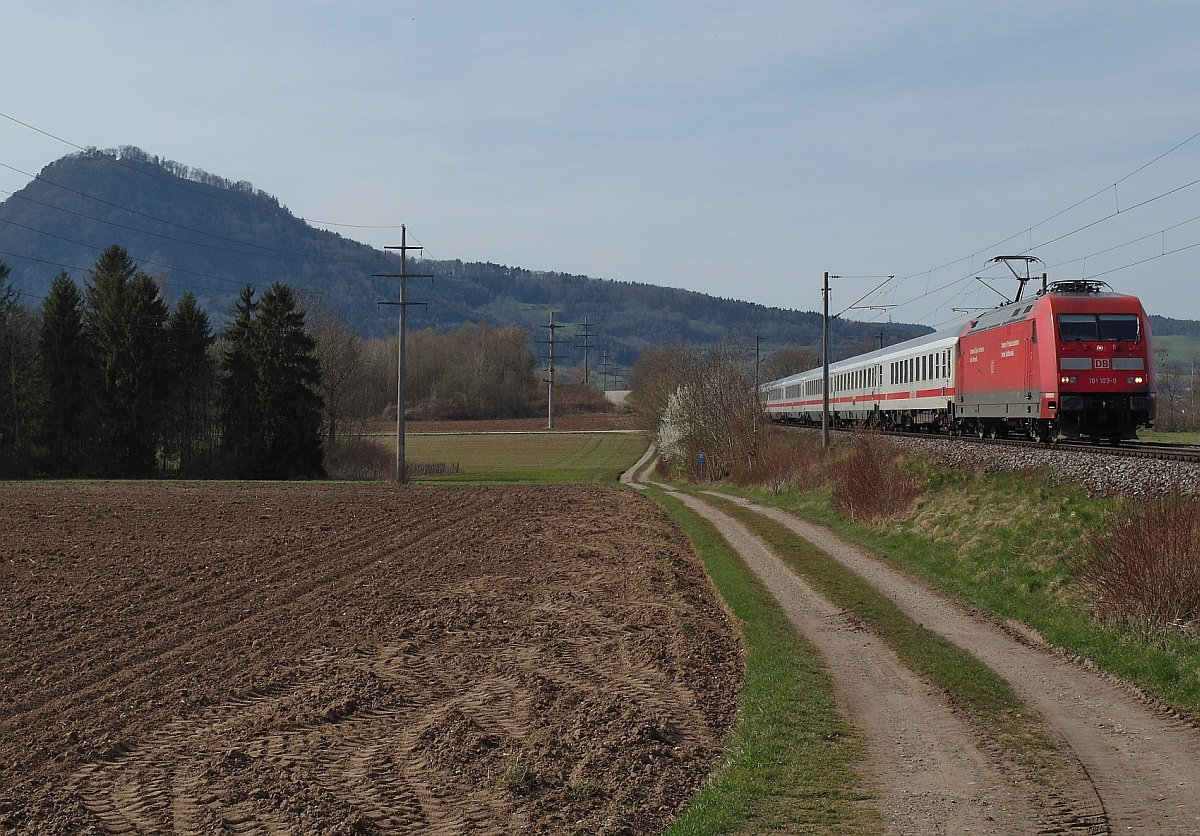 Das Ziel fast erreicht hat 101 103-0 mit dem IC 2005 'BODENSEE'  von Emden nach Konstanz. Das Bild mit dem Hausberg von Engen, dem 846 m.ü.M liegenden Hohenhewen, wurde am 10.04.2015 bei Welschingen-Mühlhausen aufgenommen.