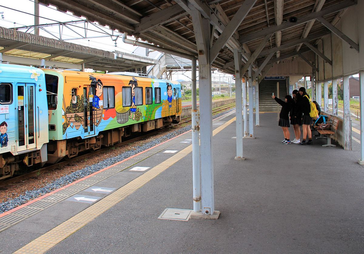 Der Dieseltriebwagen KIHA 120-9 trägt Illustrationen zu Geschichte und Kultur der Region, hier zu den Reispflanztraditionen. Eine Gruppe von Schülerinnen findet das toll und zückt gleich das Handy für ein Bild. In Ube im äussersten Westen der japanischen Hauptinsel Honshû, 8.Oktober 2015. 