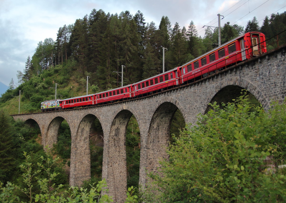 Der erste Zug des Tages, welcher die Albulabahn von Süden her befährt, ist der R 1110 (Samedan - Chur), der Filisur um 05:54 verlassen hat und sich nun auf dem Schmittentobel-Viadukt befindet. Er ist auch die einzige Personenzugleistung auf dieser Strecke, die planmäßig mit einer Ge 4/4 II gefahren wird. Hier ist es die frisch lackierte Ge 4/4 II 611  Landquart , die zwar immernoch für Login wirbt, aber in einem anderen Design.

Schmittentobelviadukt, 13. Juni 2017