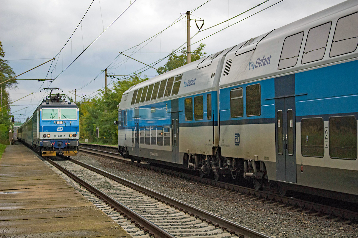 Der etwa 20 Minuten verspätete EC 173 HUNGARIA von Hamburg nach Budapest wird am 10.10.2017 von 371 003 in Richtung Süden befördert, die Verspätung dürfte noch von den Sturmschäden in Norddeutschland herrühren. Bei der Durchfahrt durch den Haltepunkt Nelahozeves zámek trifft der EC auf den ausfahrenden Os 6914, an diesem Tag liefert der City Elephant 471 067 diese Leistung