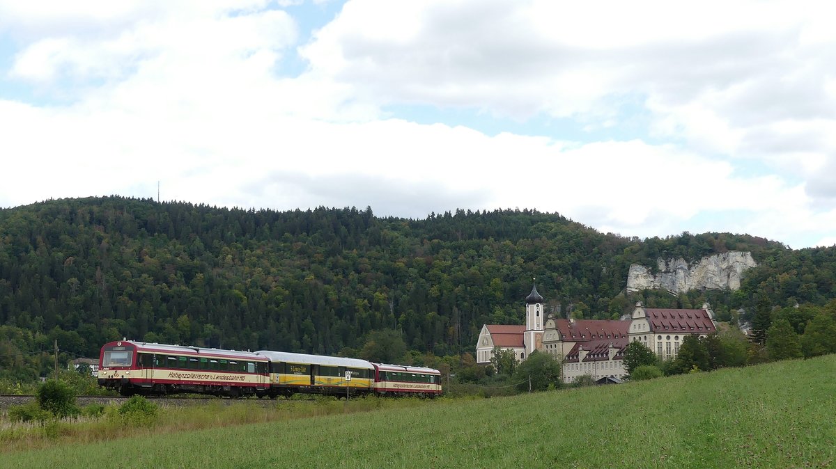 Der Hzl  Naturpark-Express  Sigmaringen - Blumberg-Zollhaus verlässt Beuron mit dessen Kloster und einigen Bergen im Hintergrund. Aufgenommen am 11.8.2018 13:04