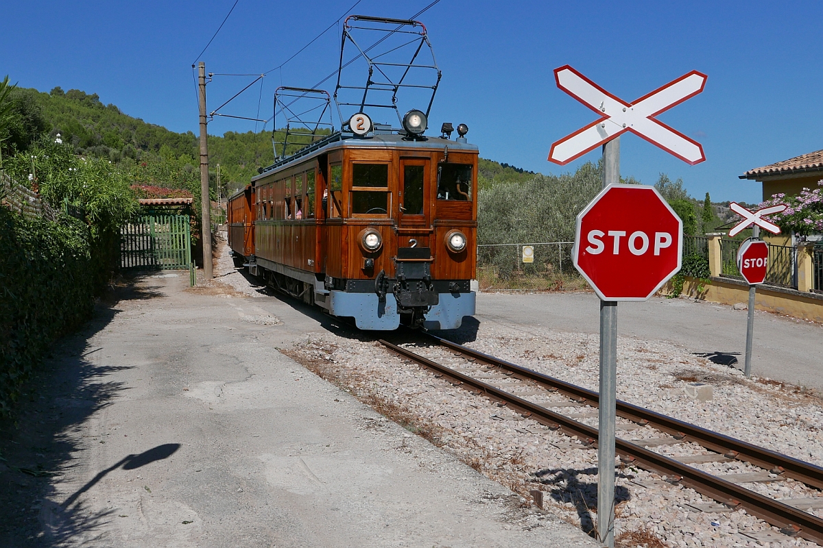 Der von Palma de Mallorca nach Sóller fahrende Zug, gezogen von Triebwagen Nr. 2, hat in wenigen Minuten sein Ziel erreicht und überquert am 19.09.2016 einen Bahnübergang im Außenbezirk von Sóller. Dieser Triebwagen ist einer von insgesamt vier elektrischen Triebwagen der Bauart AAB FHV, die ab 1929 von den Unternehmen Carde y Escoriaza (mechanischer Teil) und Siemens (elektrischer Teil) an die Ferrocarril de Sóller geliefert wurden.
