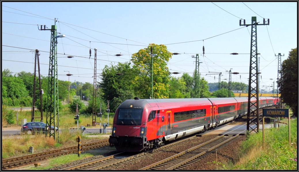 Der Railjet aus Budapest passiert hier gerade den Bahnübergang am westlichen Stadtrand von Komárom (H) auf der Kbs 1. Bildlich festgehalten wurde das Szenario Anfang August 2015.