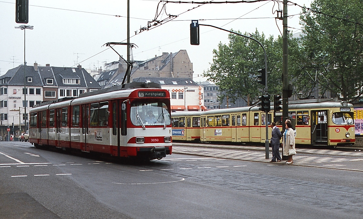 Der Rheinbahn-GT8S 3050 fährt Anfang der 1980er Jahre auf der Kasernenstraße in Richtung Kirchplatz, gegenüber wartet der GT6 2505 an der Endhaltestelle Wilhelm-Marx-Haus auf Fahrgäste nach Ratingen.