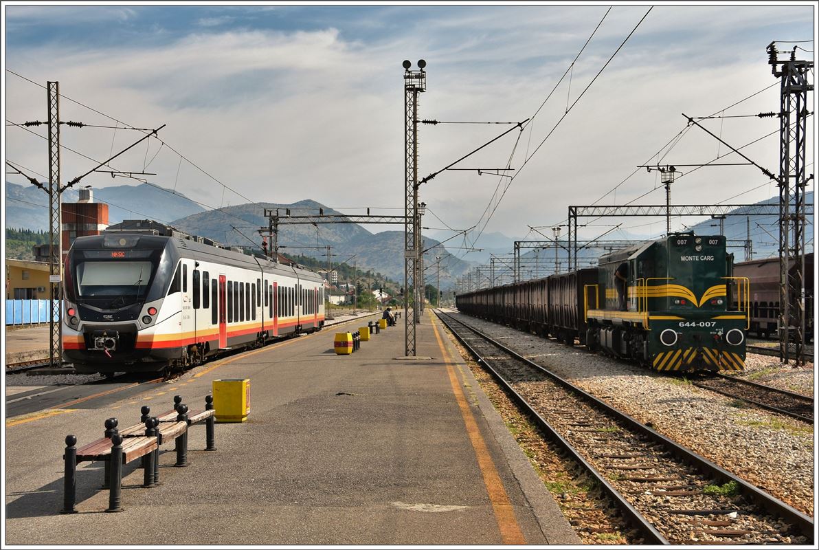 Der Triebzug 6111 107-6 wird nach Nikšić fahren. Die 644-007 hat an einen Kohlezug aus Bosnien gekoppelt. Die Fahrrichtung Süd mit Dieselbespannung kann nichts anders heissen, dass der Zug die wenig befahrene Strecke nach Hani Hotit in Albanien befährt. Der Lokführer bestätigt die Lieferung  Koks Albania , Abfahrt in  Pet minutas . Podgorica. (03.08.2016)