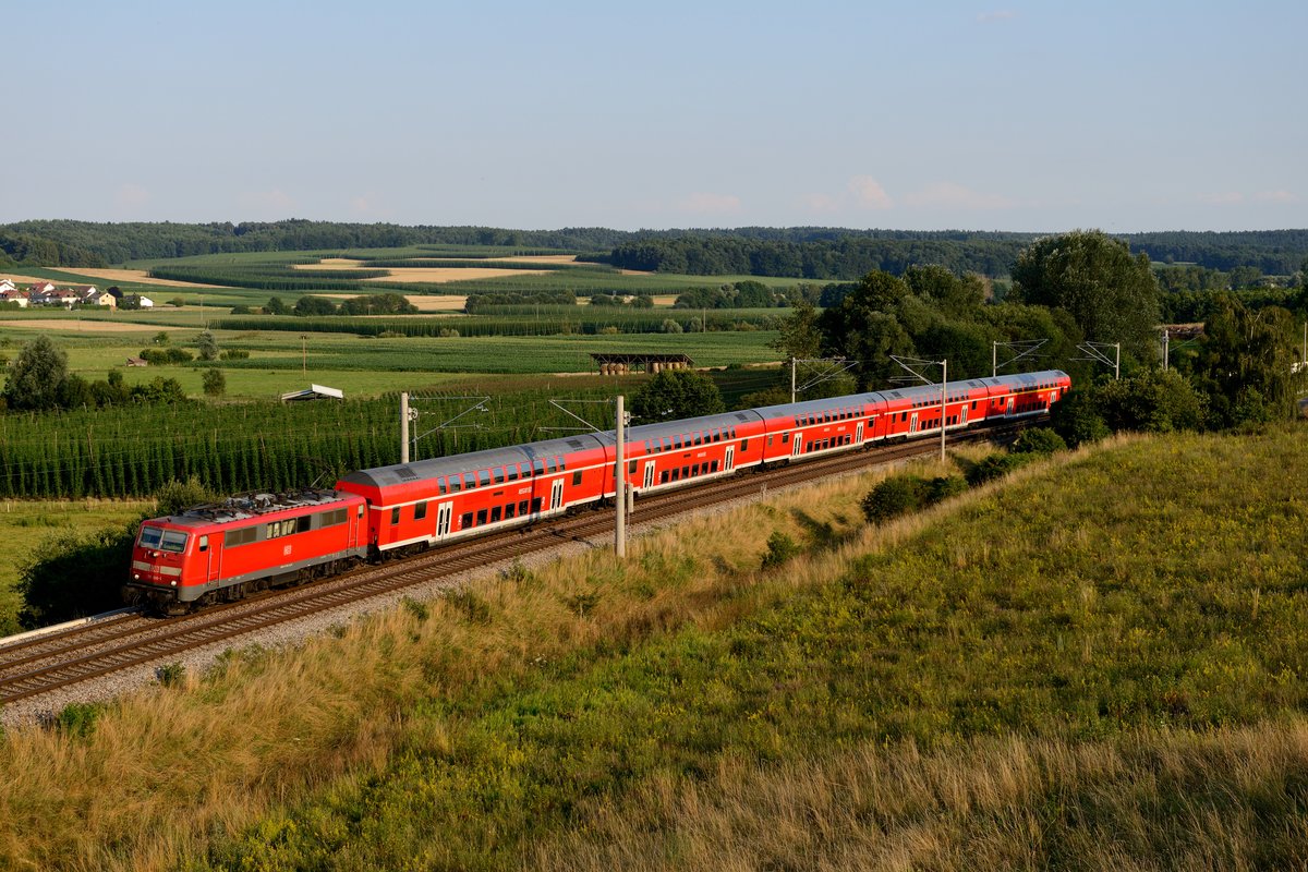 Die 111 106 mit RB 59192 hat vor kurzem dem Bahnhof Rohrbach verlassen und wird gleich die Ortschaft Fahlenbach passieren. Von einer Anhöhe aus hat man einen schönen Blick auf die typische Landschaft der Hallertau mit den charakteristischen Hopfengärten (17. Juli 2014).
 