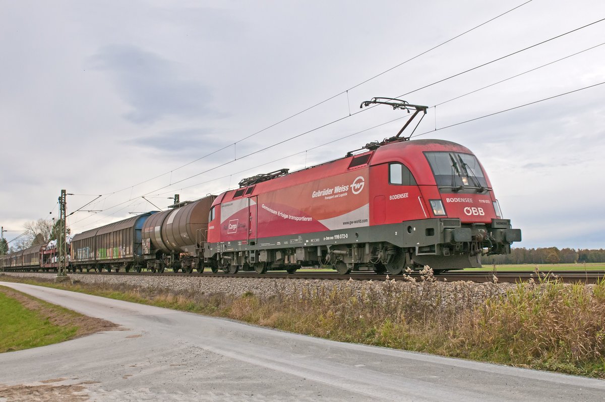 Die 1116 072-0  Gebrüder Weiss  vor einem Güterzug am 05.11.16 bei Übersee am Chiemsee.