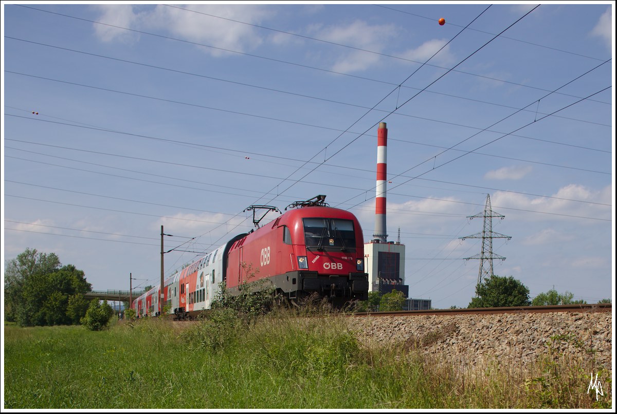Die 1116 173 mit dem Schriftzug SENSI fährt gerade mit ihrem Dosto-Zug von Retz nach Wien. Entstanden ist die Aufnahme kurz vor Bisamberg, wo im Hintergrund das kalorische Kraftwerk von Korneuburg zu sehen ist. (28.05.2015)