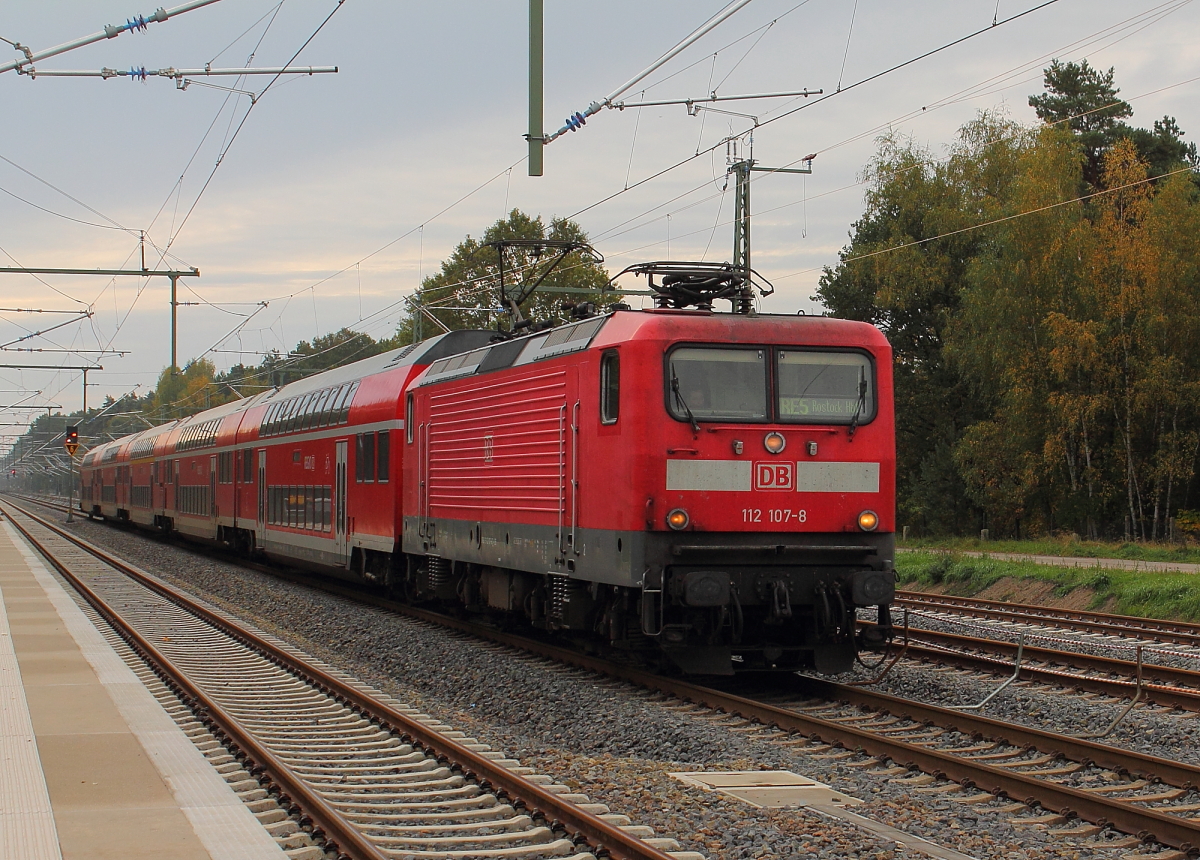 Die 112 107-8 mit dem RE 5 nach Rostock Hbf bei der Durchfahrt in Nassenheide am 13.10.2013.