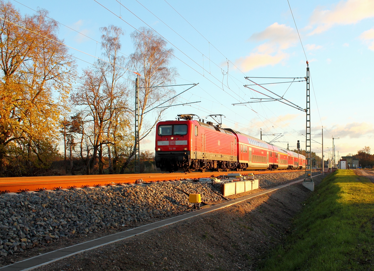 Die 112 119 mit dem RE 4360 nach Rostock Hbf bei der Durchfahrt am 25.11.2013 in Nassenheide.