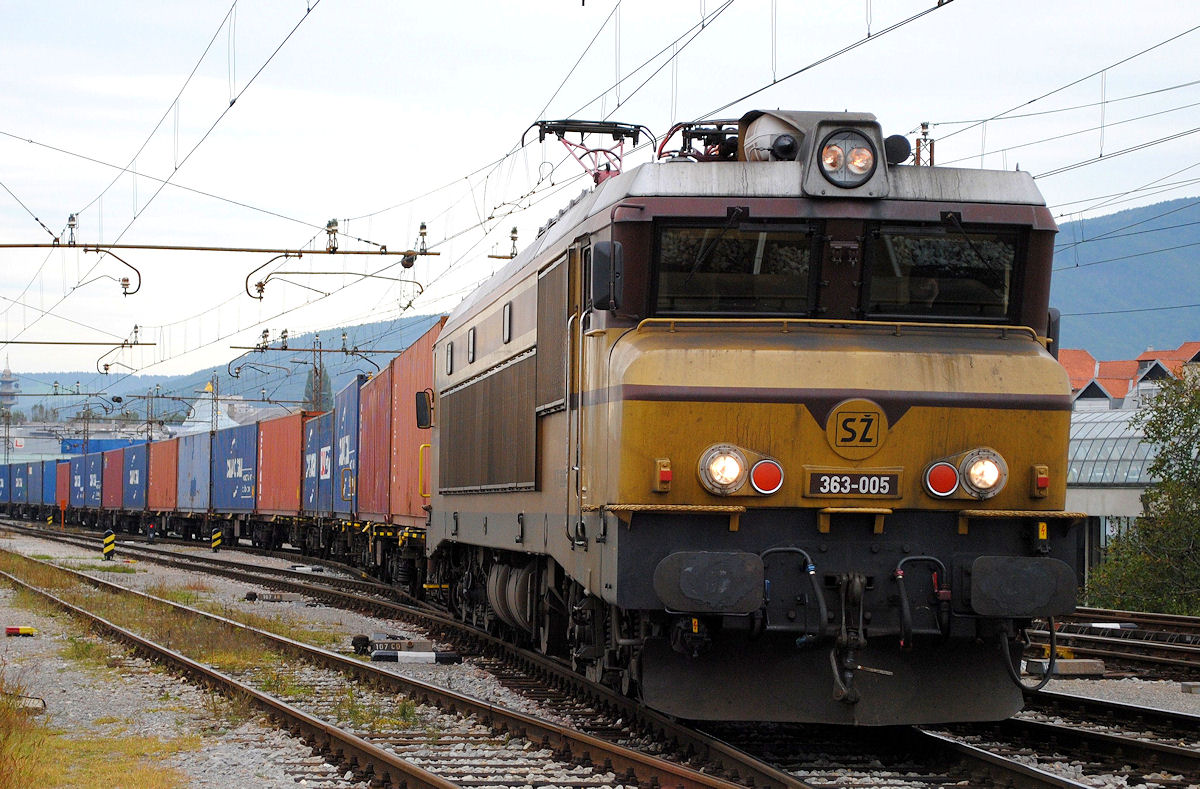 Die 363 005 besitzt mittlerweile als letzte Maschine ihrer Reihe noch die originale ockergelb/ grüne Farbgebung.
Am 26.09.2014 erreicht sie mit einem langen Containerzug den Bhf. Maribor.