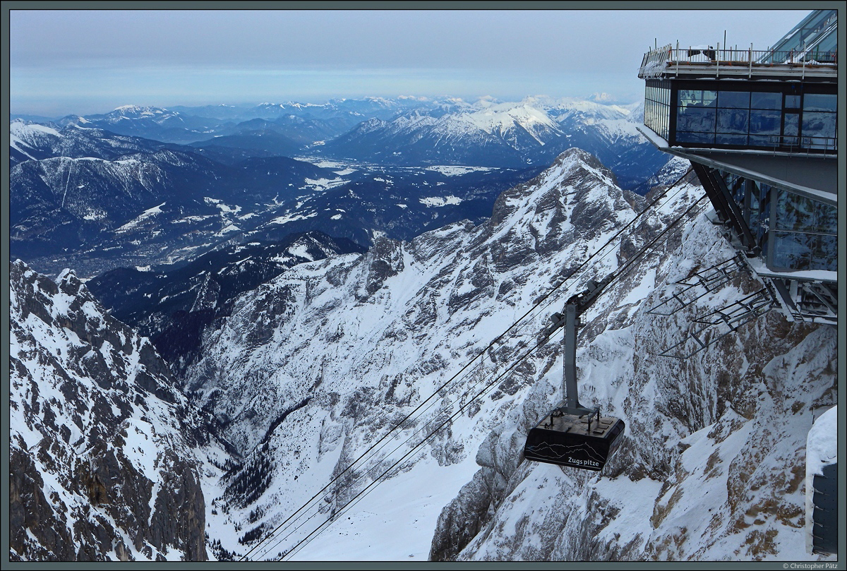Die am 21.12.2017 in Betrieb genommene Seilbahn Zugspitze verkehrt zwischen dem Eibsee und dem Zugspitzgipfel. Sie ersetzte die auf gleicher Strecke verkehrende Eibsee-Seilbahn (Baujahr 1963). Zu sehen ist eine Gondel nahe an der Bergstation. Links im Tal die Stadt Garmisch-Partenkirchen. (Zugspitze, 03.03.2018)