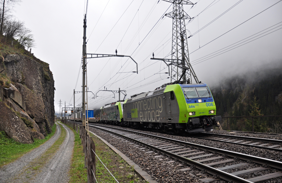 Die BLS 485 008-7 ist zusammen mit einer leider mit Graffiti versehenen Re 486 und dem neuen CargoBeamer Zug bei leichtem Nieselregen kurz vor Göschenen. Aufgenommen am 29.04.2015