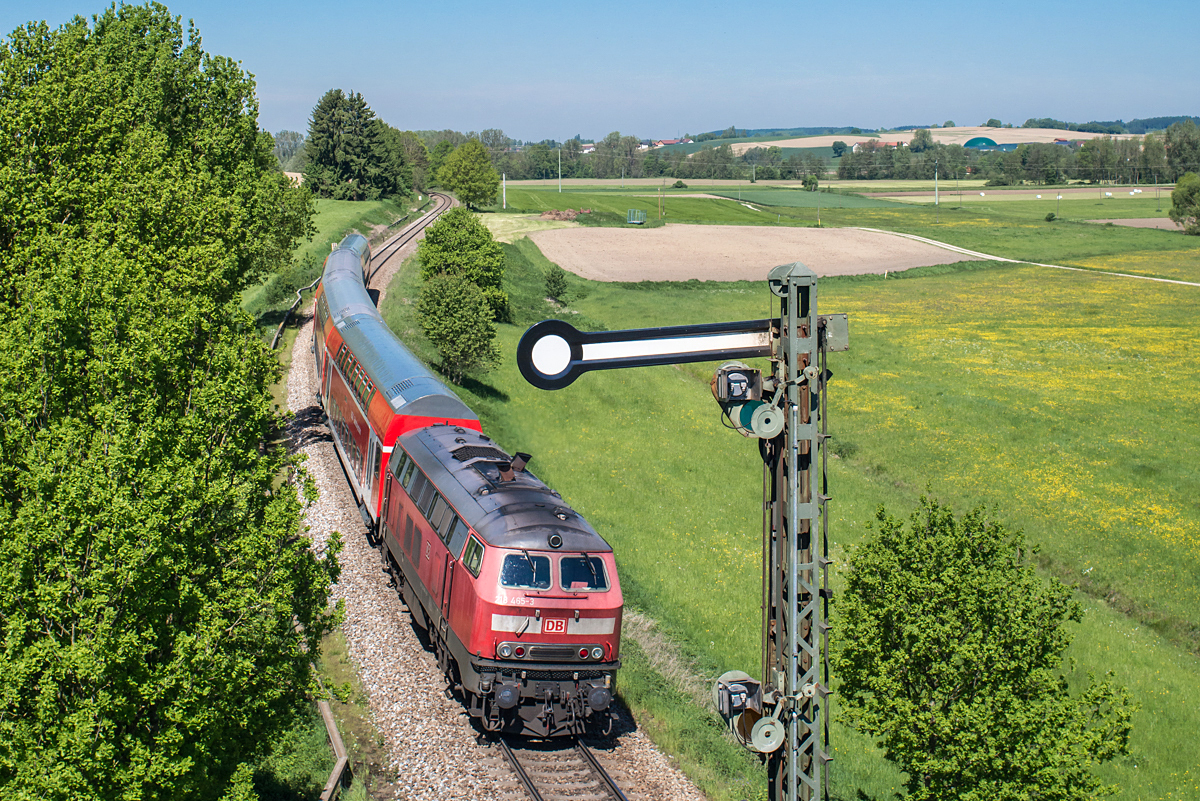 Die BR 218 ist auf der Strecke Mühldorf - München schon etwas seltener geworden, da ihre Ablöse in Form der BR 245 bereits ihren Dienst angetreten hat. Am 18.05.2017 schiebt 218 265-3 einen DoSto-RE nach München. Im Vordergrund das Einfahrsignal des Bahnhofs Schwindegg.