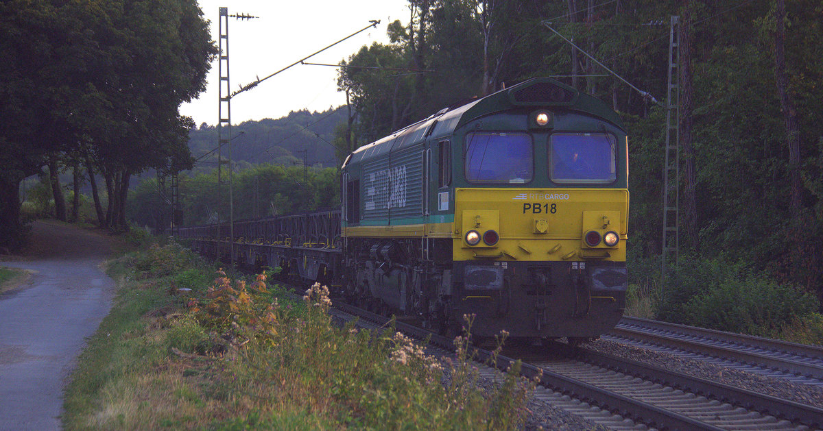 Die Class 66 PB18 von der Rurtalbahn-Cargo und kommt die Gemmenicher-Rampe herunter nach Aachen-West mit einem Kurzen Kupferleerzug aus Olen(B) nach Hegyeshalom(H). 
Aufgenommen an der Montzenroute am Gemmenicher-Weg.
In der Abendstimmung an einem schönem Sommerabend vom 23.7.2018.