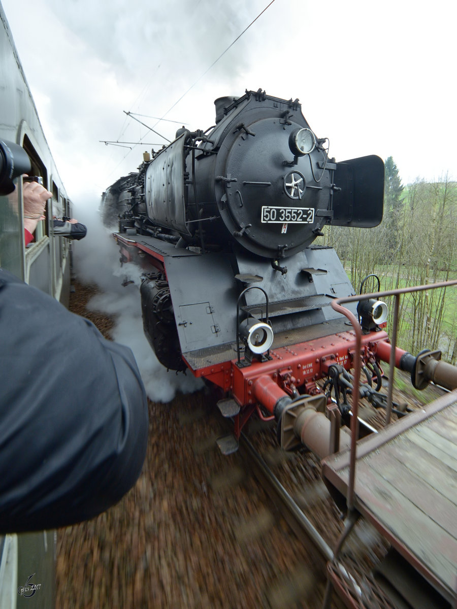 Die Dampflokomotive 50 3552-2 als Schublok für einen Güterzug während der Parallelfahrt auf der Tharanter Rampe im April 2017.