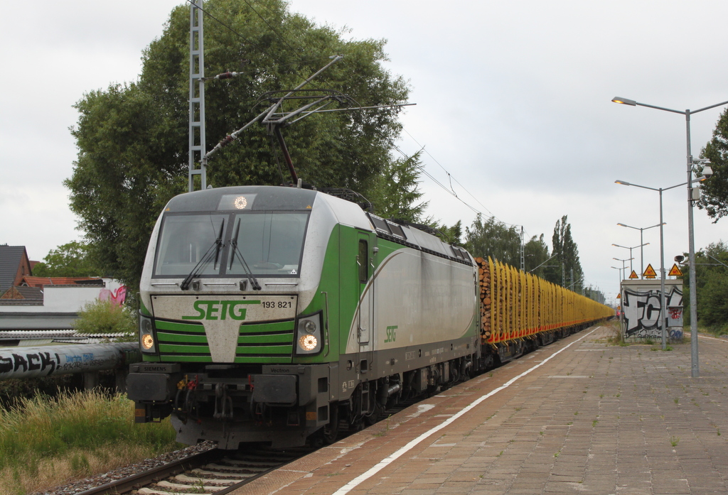 Die etwas dreckige 193 821 mit Holzzug von Rostock-Bramow nach Stendal-Niedergörne via Borstel Kr. Stendal bei der Durchfahrt im Haltepunkt Rostock-Holbeinplatz.06.07.2018