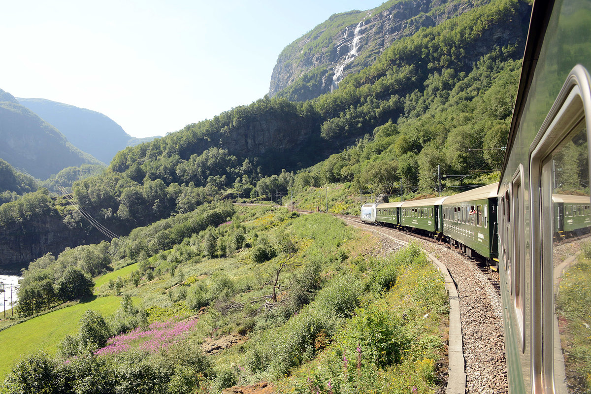 Die Flåambahn am Fureberget. Die Bahnstrecke ist 20,2 Kilometer lang und überwindet dabei einen Höhenunterschied von 864 Metern. 16 Kilometer der Strecke haben eine Steigung von über 28 ‰; die größte Steigung beträgt 55 ‰ (das entspricht einer Steigung von einem Meter auf 18 Meter Strecke). Auf diese Weise gehört die Flåmsbana zu den steilsten normalspurigen Adhäsions-Eisenbahnen der Welt.  Aufnahme: 13. Juli 2018.