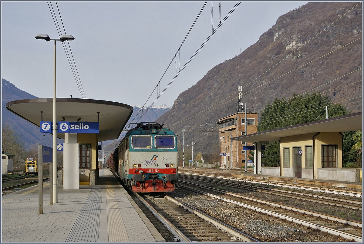Die FS Treniatlia E 652 110 steht mit einem langen Hochbordwagenzug in Premosello-Chiovenda und wartet nicht wie ich erst vermutet die Kreuzung eines Gegenzuges ab, sondern die Streckenfreigabe Richtung Stresa, dies ist insbesondere interessant, da der Zug auf der  Novara  Strecke in Premosello-Chiovenda angekommen ist.
29. Nov. 2018