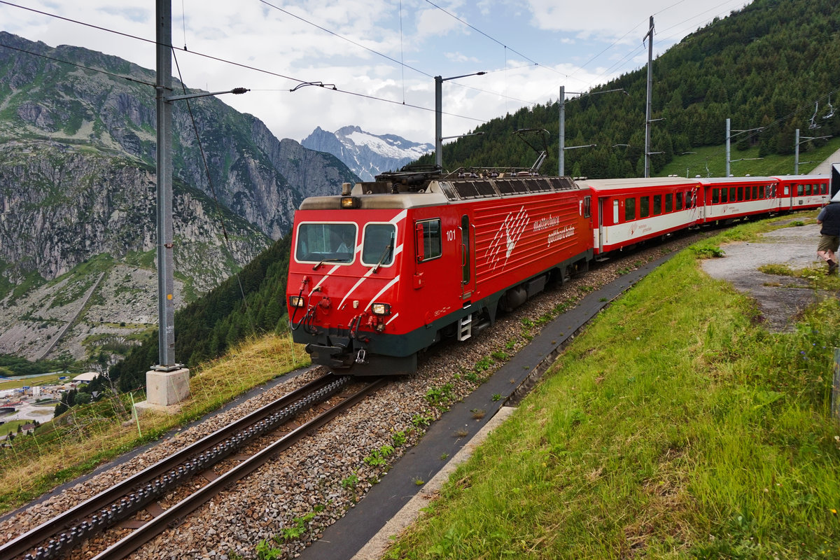 Die HGe 4/4 101, taucht mit dem talwärts fahrenden R 819 (Disentis/Mustér - Andermatt), oberhalb von Andermatt aus dem Grind-Tunnel auf.
Aufgenommen am 21.7.2016.