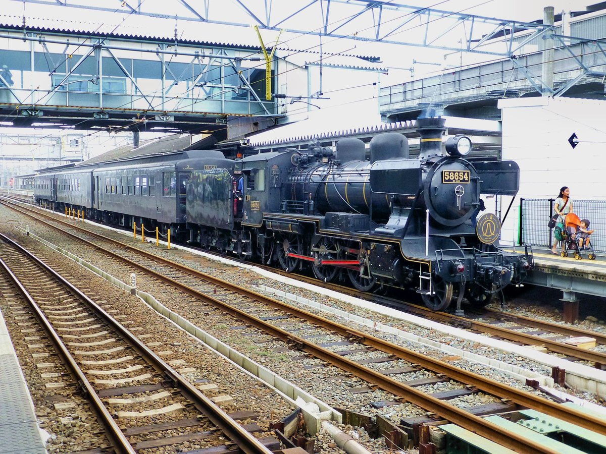 Die japanische Dampflok 5-8654 (Typ 8620): Diese Lok ist die einzige 8620, die noch (ausserhalb eines Museums) in Betrieb zu sehen ist. Sie ist auch die einzige betriebsfähige Dampflok auf der japanischen Südinsel Kyûshû. Sie hat eine Höchstgeschwindigkeit von 95 km/h und 759 PS. Erbaut 1922, ausgemustert 1975, Wiederinbetriebnahme 1988. Hier steht sie mit ihrem Zug in der Stadt Kumamoto, von wo aus sie rund 2 1/2-stündige Fahrten in die Berge unternimmt. Wie man rechts sieht, sind schon die Allerkleinsten von der Dampflok fasziniert! 29.Juli 2013  HISATSU-LINIE 