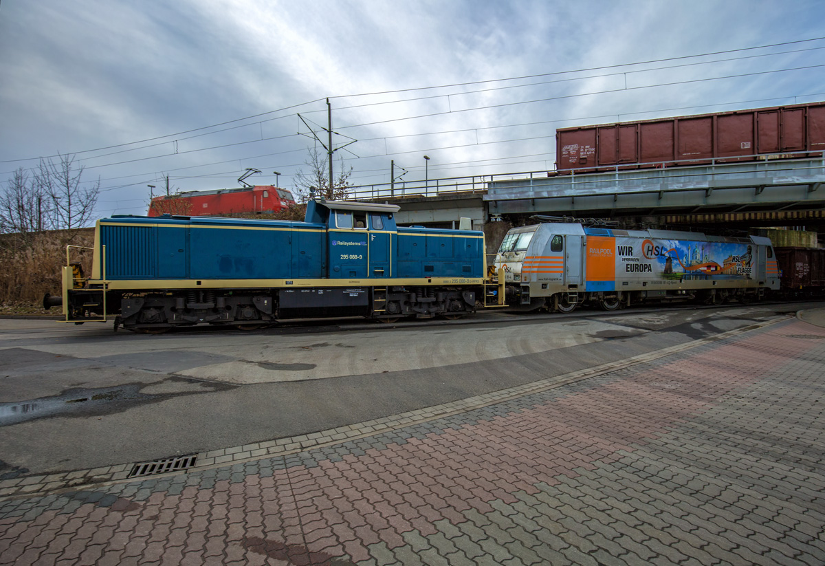 Die Rangierlok der BR 295 ist mit der E-Lok der BR 186 und Ea-Wagen auf der Rangierfahrt vom Südhafen zum oben zu sehenden Bahnhof Stralsund Rügendamm. - 22.02.2017
