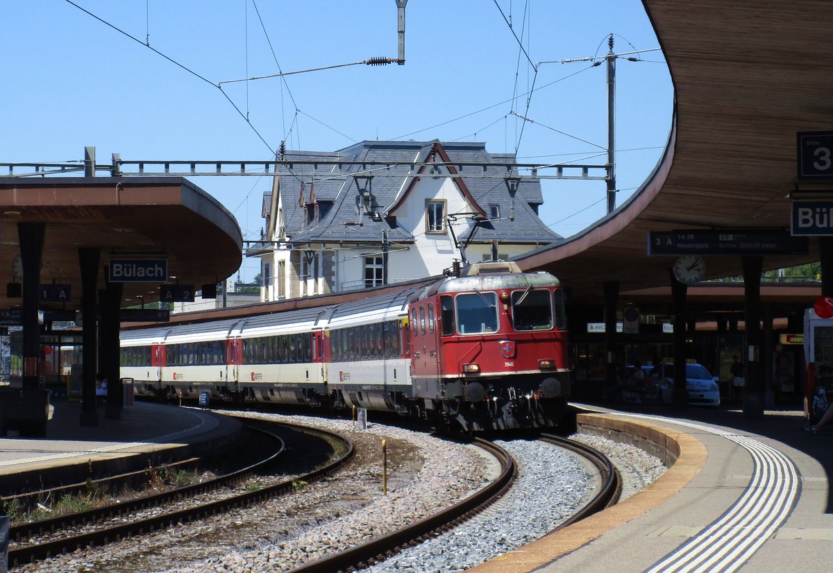 Die SBB Re 4/4 II Nr. 11140 durchfährt am 26. Mai 2017 unter blauem Himmel mit dem IR 2823 von Schaffhausen- Zürich HB den Bahnhof Bülach.
    