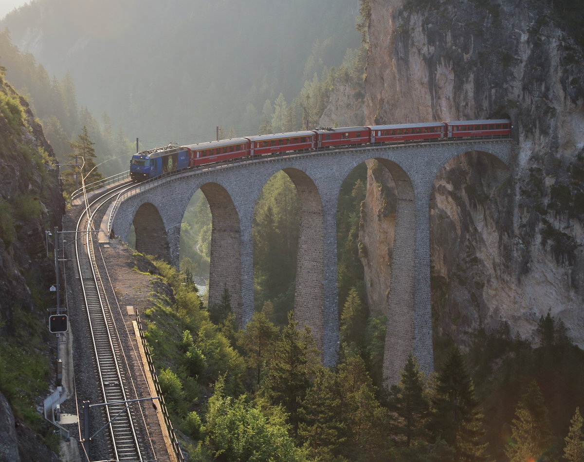 Die Sonne ist gerade aufgegangen, da schiebt sich Ge 4/4 III 652  Vaz/Obervaz
Lenzerheide-Valbella  mit dem R 1114 (St.Moritz - Chur) aus dem Landwassertunnel auf das Landwasserviadukt. 

Landwasserviadukt, 13. Juni 2017