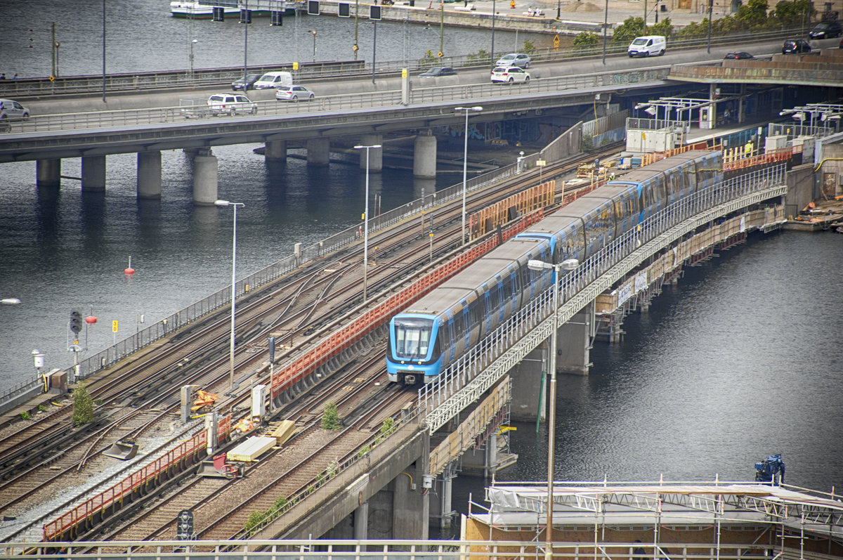 Die Stochkholmer Tunnelbana vom Katharinahissen aus gesehen. Auf der Brücke über Söderström ist ein Zug der neuesten Baureihe C20 der Tunnelbana zu sehen. Aufnahme: 24. Juli 2017.