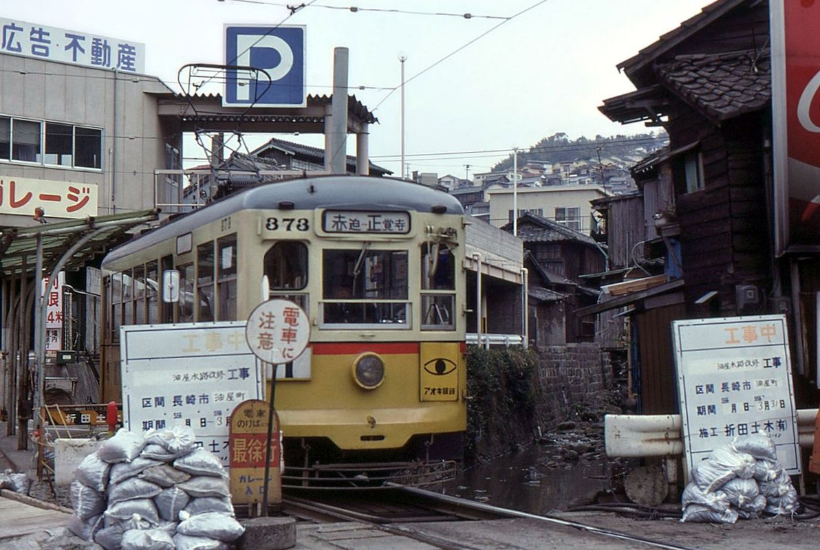 Die Strassenbahn von Nagasaki - An der Endstation der mittleren Strecke in die Berge hinein nach Shôkakuji-shita wartet Wagen 373 (Serie 371-377) auf die Rückfahrt. Typisch für Nagasaki ist die Baustellenatmosphäre, um die steilen Hänge zu stabilisieren. Nagasaki hat schon öfter schwere Hangrutschkatastrophen erlebt, besonders bei heftigen Regenstürmen. Nicht zu übersehen ist, dass diese weit weg von Tokyo im extremen Westen liegende Stadt von einer gewissen Armut gekennzeichnet war. 18.März 1981.   