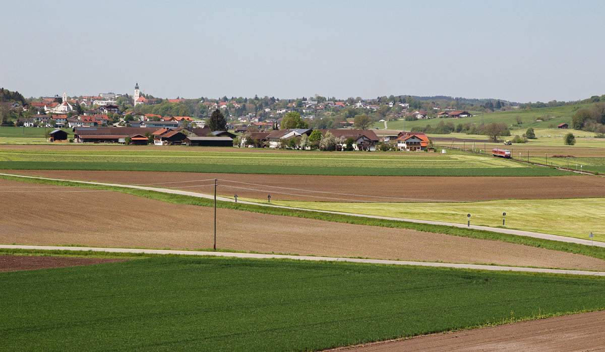 Dieses Bild beinhaltet gleich 3 Ortschaften auf einmal:
Im Vordergrund der kleine Ort Neuhausen, dahinter Oberndorf mit seiner Kapelle links im Bild. Im Hintergrund erkennt man Ebersberg mit seinem schönen Kirchturm. 
628 596-9 strebte am 07.05.16 ganz nebenbei die Steigung aus Steinhöring heraus die Ortschaft Oberndorf (ohne Bahnhof) an.