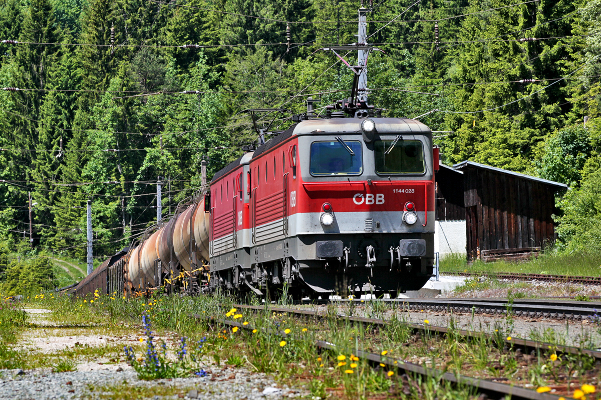Doppeltraktion der beiden Lokomotiven 1144 028 und der 1144 043-7 fähren mit einem gemischten Güterzug in Wald a/A vorüber.Bild vom 10.6.2016