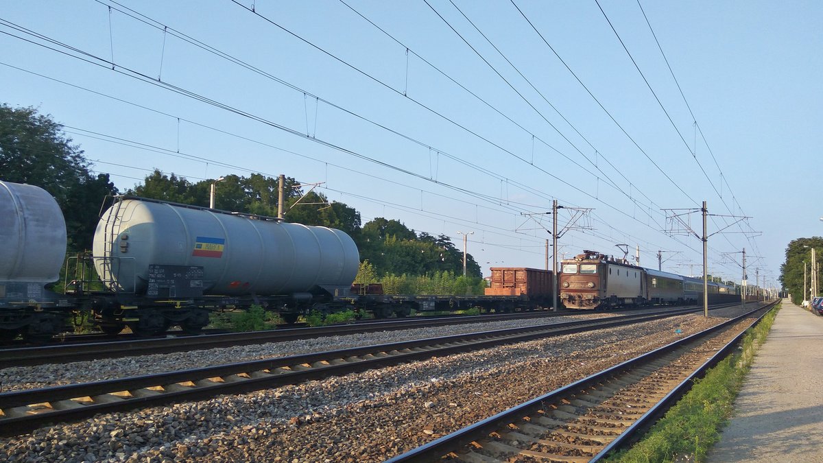 E-Lok 45-0379-3 mit Interregio aus Richtung Constanta durchfährt am 09.08.2017 den Bahnhof Bucuresti Baneasa. Daneben steht auf ein Ziehgleis abgestellt ein Güter-Sondertransport, von dem in diesem Bild ein Kesselwagen und ein leerer Containerwagen.