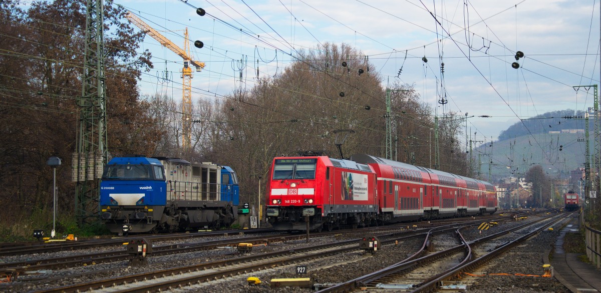 Ein Regionalexpress mit 146 220 Richtung Ulm unterwegs, eine abgestellte MaK G2000BB passierend, gesehen am 18.12.2013 am Nordkopf des Heilbronner Bahnhofs. 