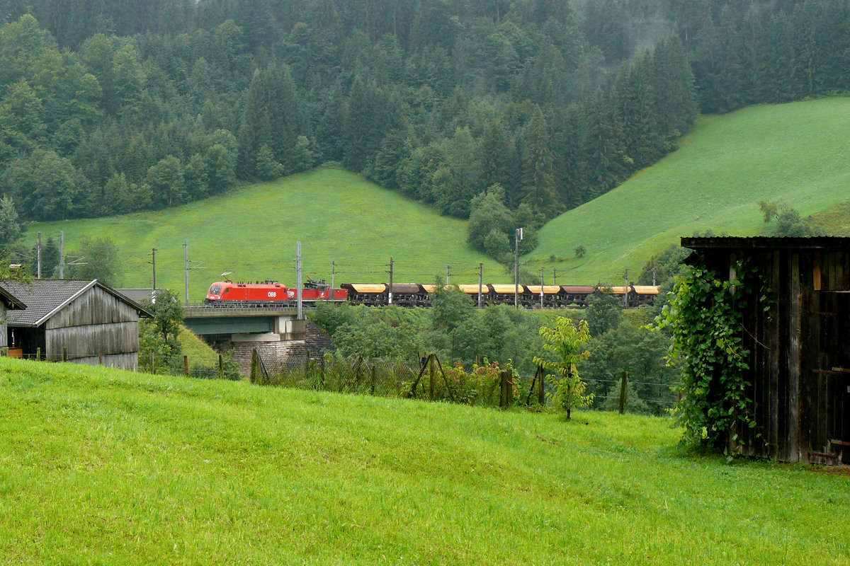 Ein schwerer Güterzug mit der 1016 039 in Front kämpft sich bei Unterwindau die Kehren hoch in Richtung Brixen. Das Bild entstand am 06/08/2010.