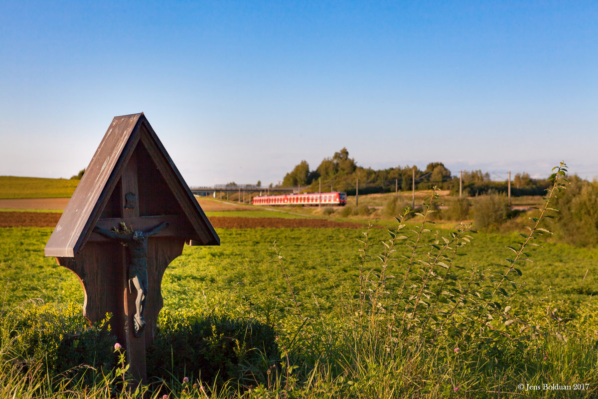 Ein unbekannter Quietschie der Baureihe 423 zieht an einem typisch bayerischen Wegkreuz (Marterl) bei Hebertshausen vorbei