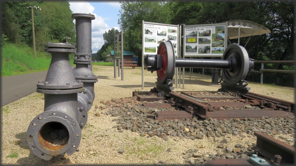 Ein wenig  Bahngeschichte  neben dem Vennbahnradweg gibt es in Pronsfeld in der Eifel zu bewundern. Hier ein Industrierohr und eine Radachse. Informationstafeln laden zum Lesen und Verweilen ein. Datiert vom 21.August 2017.