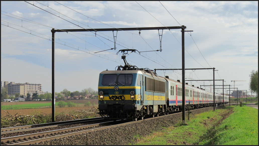 Eine belgische Reeks 27 ist mit einen Regionalzug am Haken unterwegs nach Hasselt.
Hier zu sehen unweit von Tongeren am 21.April 2016.