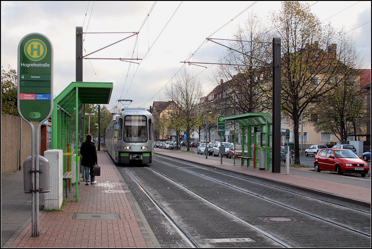 Einstieg über Klapptrittstufen - 

Als in den siebziger und achtziger Jahren das Straßenbahnnetz nach und nach auf Stadtbahnbetrieb umgestellt wurde, erhielten lediglich die U-Haltestellen und die meisten Endstationen Hochbahnsteige (nur der Abzweig nach Alte Heide hatte von Anfang an erhöhte Bahnsteige). Die Haltestelle Hogrefstraße an den Linien 4 und 5 zeigt ein typisches Aussehen der damals modernisierten Haltestellen. Noch gibt es eine Großzahl von Haltestellen bei denen die Klapptrittstufen zum Einsatz kommen müssen. 

2013 wurde diese Haltestelle und die weiter stadteinwärts liegende Haltestelle Hemelingstraße durch die neue Station Freudenthalstraße mit zwei Seitenhochbahnsteige ersetzt.

02.11.2006 (M)