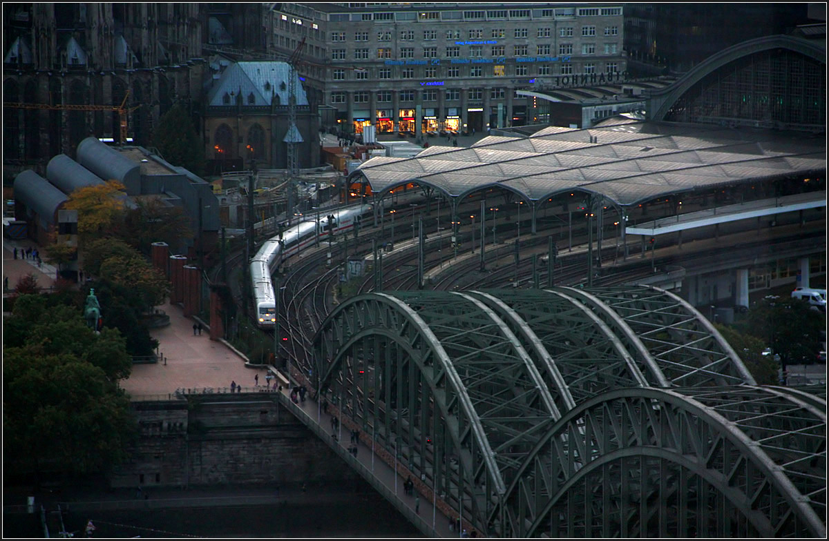 Enger Bogen -

Da man die Hohenzollernbrücke direkt in der Flucht des Kölner Domes baute (so kann der Lokführer schön auf diesen blicken, während ihn die Fahrgäste nicht sehen können) musste ein recht enger, betrieblich ungünstiger Bogen vor den Bahnsteigen des Hauptbahnhofes gebaut werden. Blick vom Kölntriangle-Hochhaus auf die Bahnanlagen mit ausfahrendem ICE.

06.10.2014 (M)