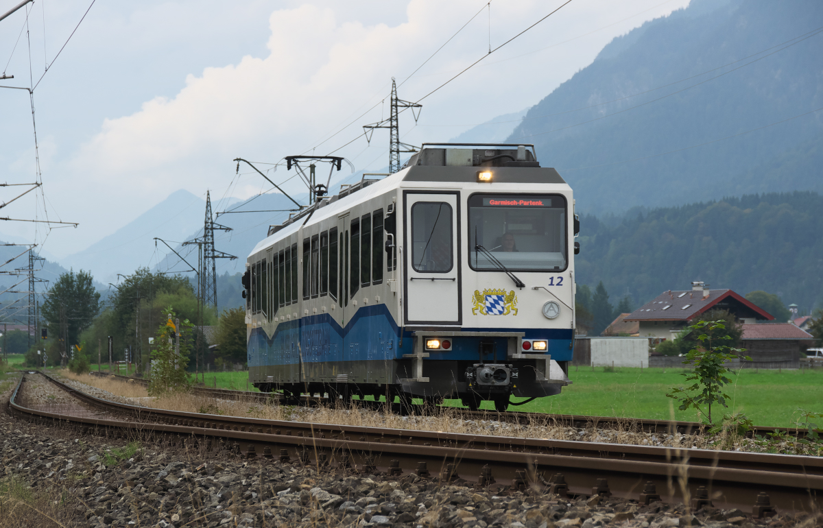 Etwas mehr als 3 Kilometer verlaufen die Außerfernbahn nach Reutte in Tirol und die meterspurige Bayerische Zugspitzbahn parallel. Tw 12 der Zugspitzbahn hat den Haltepunkt  Hausberg  verlassen und fährt Richtung Garmisch-Partenkirchen weiter. 16.09.2016