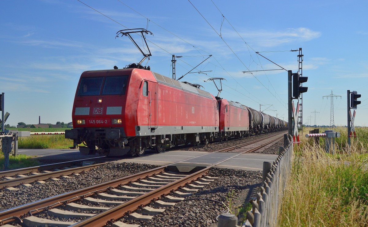 Für die BASF haben die 145 064-2 uns 185 066-8 einen Kesselwagenzug am Haken, als sie am Freitag den 10. Juli 2015 am Bü Am Chur/In der Schley bei Wickrathhahn gen Rheydt fahrend zu sehen sind.