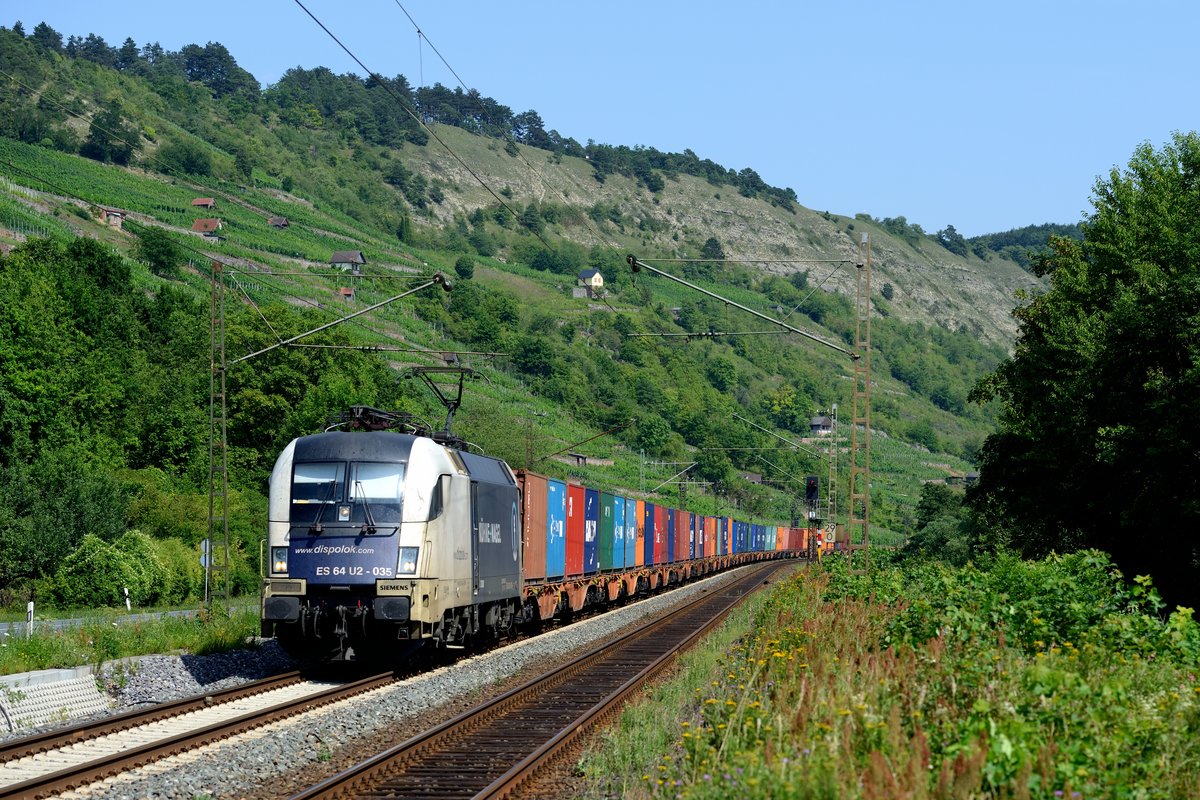 Für Wiener Lokalbahn Verhältnisse befindet sich ES 64 U2 035 in einem halbwegs akzeptablem Pflegezustand. Die Lok mit der Kühne + Nagel Seitenwerbung beförderte am 19. Juli 2014 den Samstags verkehrenden DGS 43950 von Enns Hafen nach Dradenau, hier aufgenommen bei Gambach im sommerlichen Maintal.