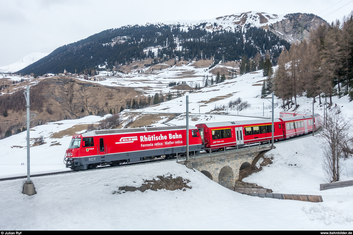 Ge 4/4 III 647 mit RE St. Moritz - Chur am 17. März 2018 oberhalb Bergün. Im Hintergrund das Heididorf Latsch.